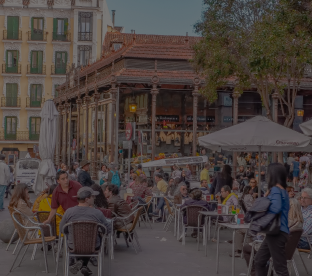 Una plaza repleta de mesas de bar y clientes